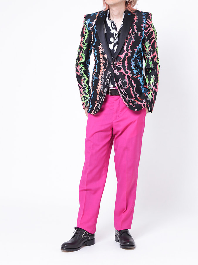 黒地に蛍光ピンク・ブルー・グリーンなどのゆがんだラインがランダムにあしらわれたジャケットと濃いピンク色のスラックスのスーツスタイル（Just Cavalli）